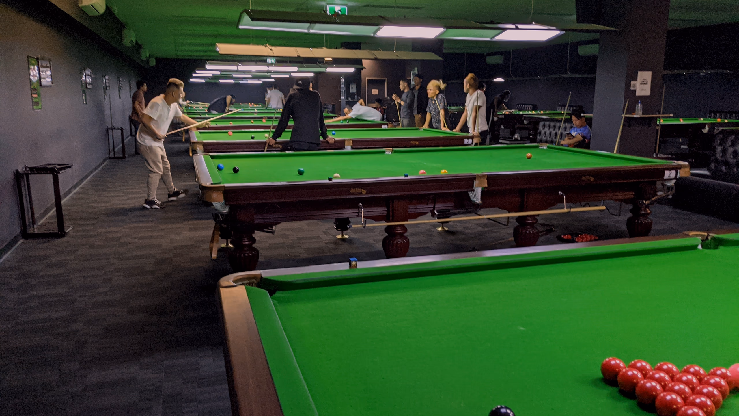A rack of reds on the near table, the row of tables and light rafts running away behind it with players at the far end.